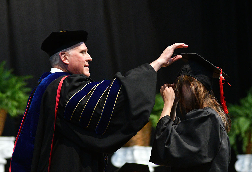 David Kurpius, the Journalism School dean, holds Chengcheng Yao's mortarboard